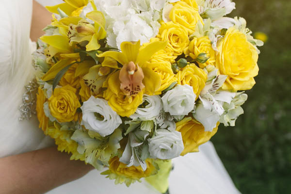 A spring garden bouquet in varied shades of yellow.   bouquet white flowers create a subtle contrast against the yellow craspedia.  The white ranunclus, fever few and ivory stock, soften the colors with accents of seeded eucalyptus.